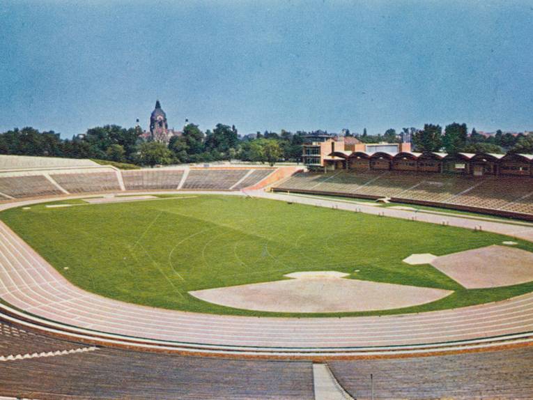 Postkarte (Ausschnitt) des Niedersachsenstadions am Arthur-Menge-Ufer. Das Bild ist von einer Position im Bereich der obersten Sitzplätze aufgenommen und zeigt das Innere des Stadions, im Hintergrund ist der Turm des Neuen Rathauses zu sehen. 1954-1965